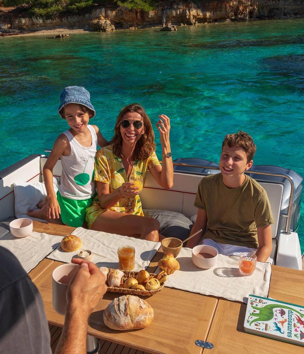 Familie bei einem sommerlichen Bootsausflug auf dem Wasser mit Frühstück